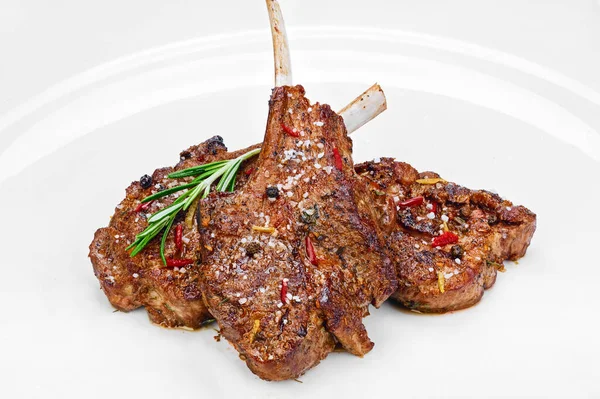 Beyaz arka planda siyah ve kırmızı biberli kızarmış sığır kaburgası, tuz ve yeşil otlar.
