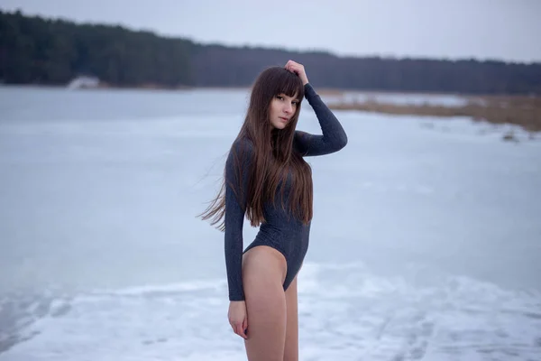 暗いグレーのボディー スーツ冬に屋外でポーズとカメラ目線で美しい若い女性 — ストック写真
