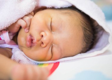 Bebek kanepede bir battaniyenin altında yatıyordu.