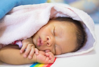 Bebek kanepede bir battaniyenin altında yatıyordu.