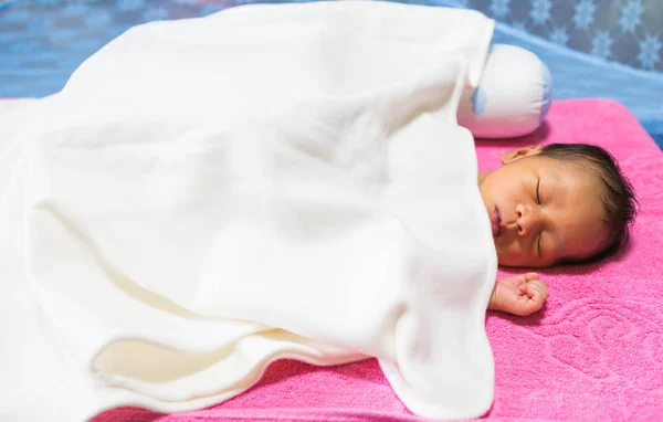Şilte üzerinde bir battaniyenin altında yatan bebek.