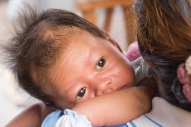 Çocuk, annesinin omzuna yalan söylüyor.