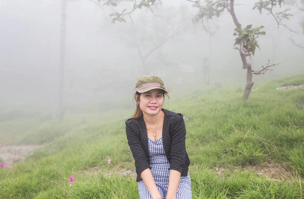 A woman sitting on a mountain in the morning with fog.