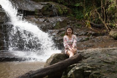 Ormandaki bir kayaya oturan kadın.