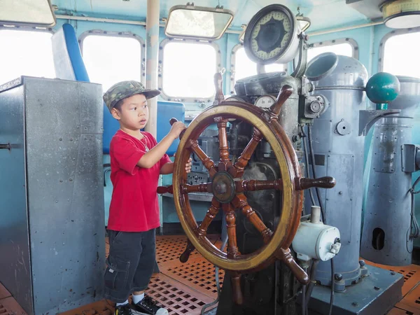 Çocuk savaş gemisinin dümenini kontrol ediyor..