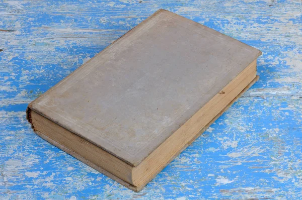 Vintage book in gray binding on a blue wooden background .. Front view.