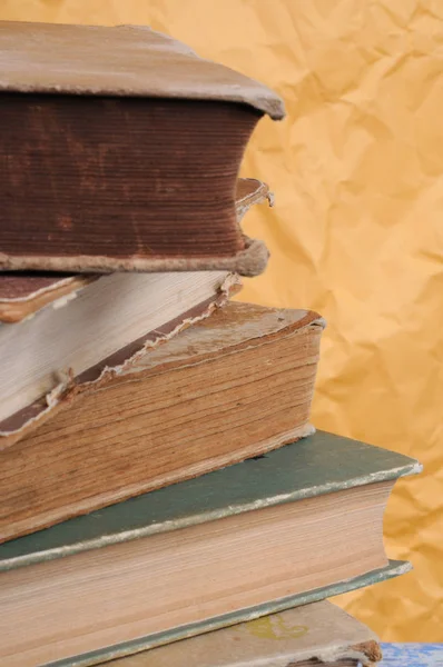 A stack of old books on a yellow background. Front view.