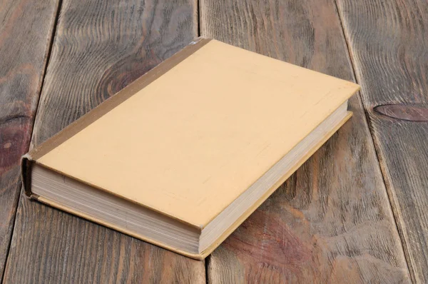 A book in yellow binding on a wooden background. Front view.
