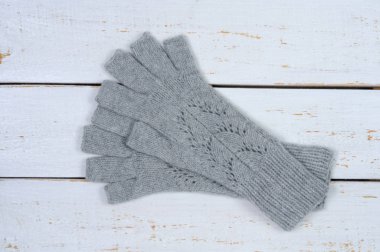 Beyaz ahşap zemin üzerine açık parmaklı örme gri eldiven. İşlemeli. Yukarıdan görüntülemek.