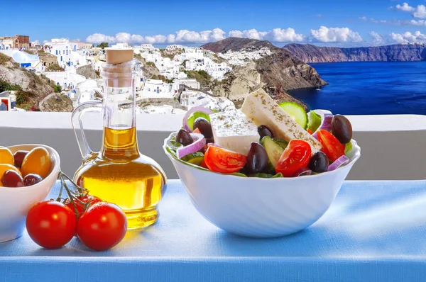 Greek salad against famous Oia village, Santorini island in Greece