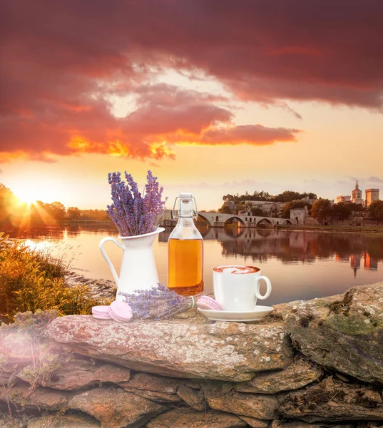 Lavender still life with cup of coffee against Avignon bridge in Provence, France