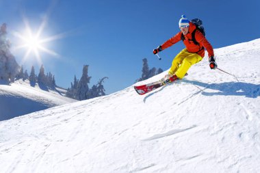 Yokuş aşağı mavi gökyüzü karşı yüksek dağlarda kayak kayakçı