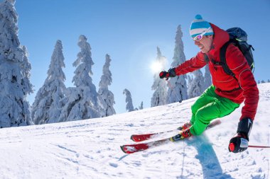 Yokuş aşağı mavi gökyüzü karşı yüksek dağlarda kayak kayakçı