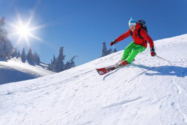 Yokuş aşağı mavi gökyüzü karşı yüksek dağlarda kayak kayakçı