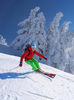 Yokuş aşağı mavi gökyüzü karşı yüksek dağlarda kayak kayakçı