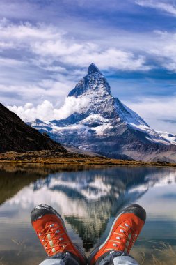 Matterhorn peak with hiking boots in Swiss Alps. clipart