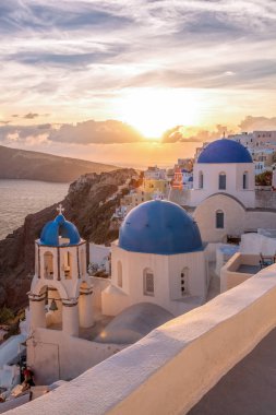 Yunanistan 'ın Santorini adasında gün batımına karşı kiliseleri olan Oia köyü