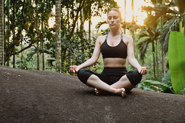 Genç kız ormanda gün batımında yoga yaparken — Stok fotoğraf