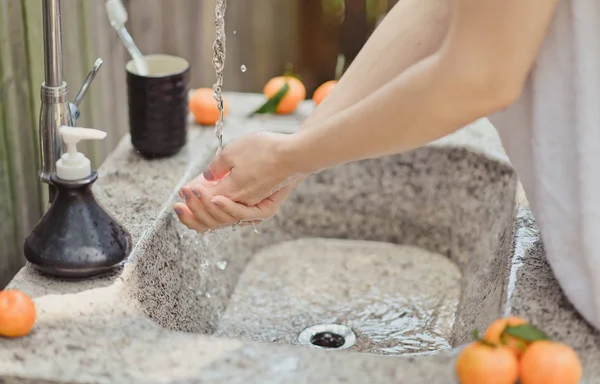 Frau wäscht ihr Gesicht mit Wasser. Badezimmer im Freien — Stockfoto