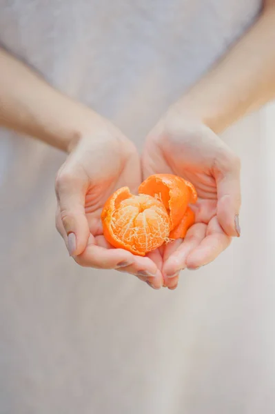 Fresh mandarin oranges fruit or tangerines. Female hands holding ripe mandarins, close up