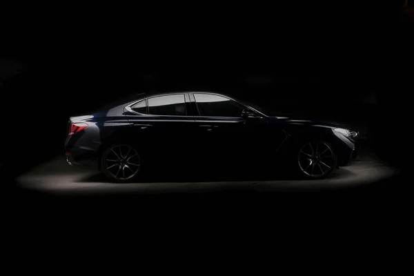 silhouette of black sports car with headlights on black background