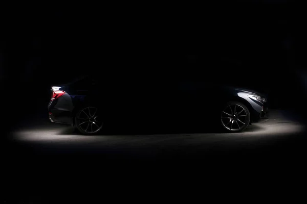 Silhouette de voiture de sport noire avec phares sur fond noir — Photo