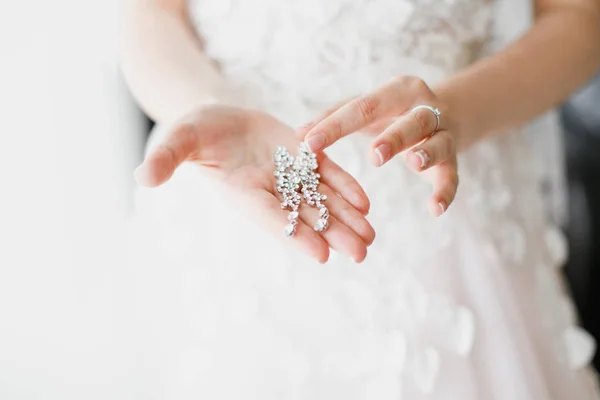 Orecchini primo piano nelle mani della sposa. accessori gioielli — Foto Stock