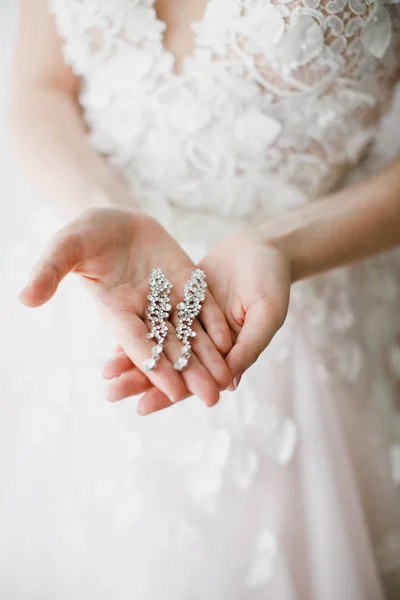 Pendientes de cerca en las manos de la novia. accesorios de joyería —  Fotos de Stock