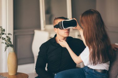 Genç çift birlikte oturma odasında VR oynayarak vakit geçiriyor. 