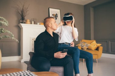 Genç çift birlikte oturma odasında VR oynayarak vakit geçiriyor. 