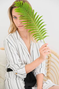 kız yüzünde bir yaprak tutar. Yüzünü yaprakla kaplayan bir kadının portresi