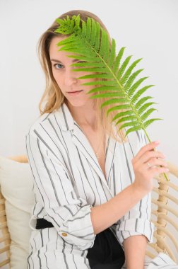 kız yüzünde bir yaprak tutar. Yüzünü yaprakla kaplayan bir kadının portresi