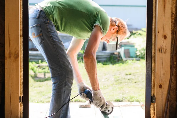 Bouwer werknemer met Grinder machine snijden metaal hout op bouwplaats — Stockfoto