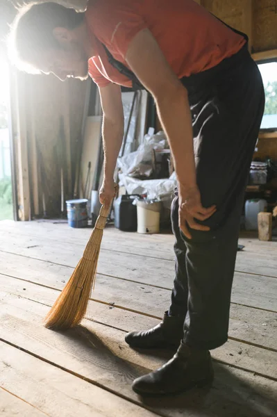 Man veegt de houten vloer. schuur reiniging — Stockfoto