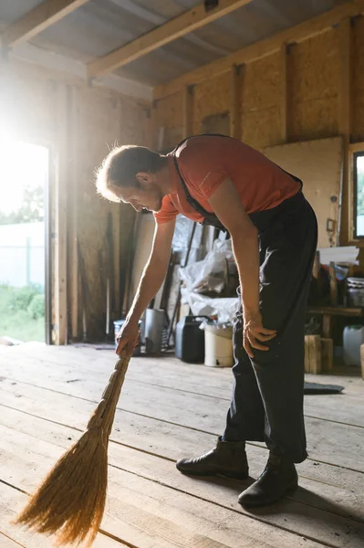 Man veegt de houten vloer. schuur reiniging — Stockfoto