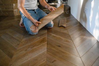 Parke döşeme döşeyen adam, erkek ellerine yakın plan. Parke zeminine katılan işçiler