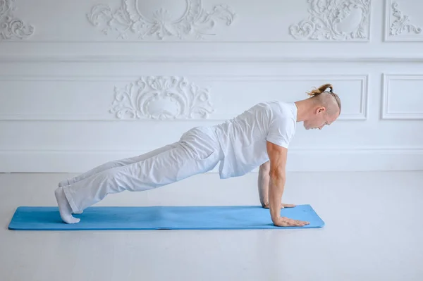 Mann praktiziert fortgeschrittenes Yoga vor weißem Hintergrund — Stockfoto