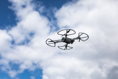Beyaz bulutlarla mavi gökyüzüne karşı quadrocopter. Gökyüzündeki helikopterin uçuşu
