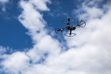 Beyaz bulutlarla mavi gökyüzüne karşı quadrocopter. Gökyüzündeki helikopterin uçuşu