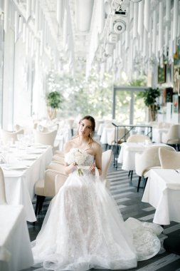 elinde bir buket ile güzel gelin, bir restoranda oturur