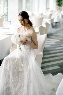 elinde bir buket ile güzel gelin, bir restoranda oturur