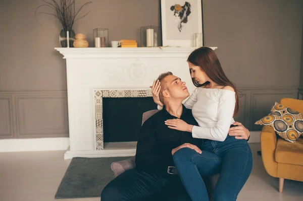 O homem e a mulher felizes sentam-se no fundo da lareira branca — Fotografia de Stock