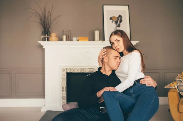 O homem e a mulher felizes sentam-se no fundo da lareira branca — Fotografia de Stock