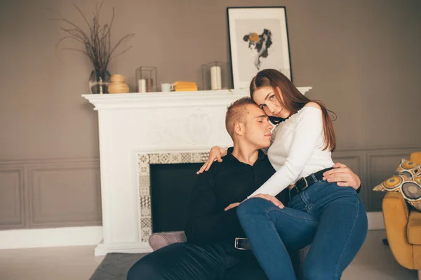 O homem e a mulher felizes sentam-se no fundo da lareira branca — Fotografia de Stock