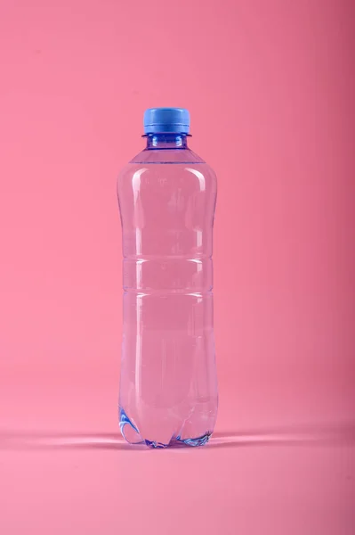 Пластиковая бутылка здоровой воды на розовом фоне — стоковое фото