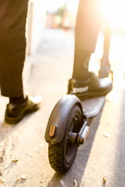 Benen van een man in stijlvolle outfit staan op elektrische scooter op straat — Stockfoto