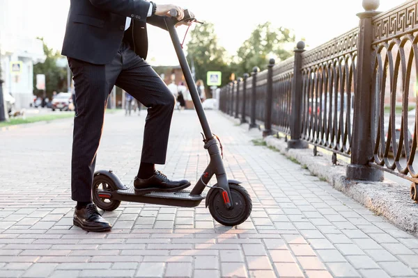 Pernas de um homem em estande de roupa elegante em scooter elétrico na rua — Fotografia de Stock