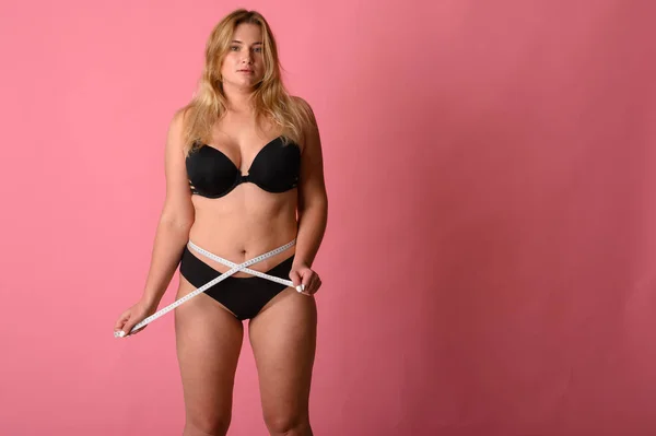 Girl wearing black bikini measures the size of the waist — Stock Photo, Image