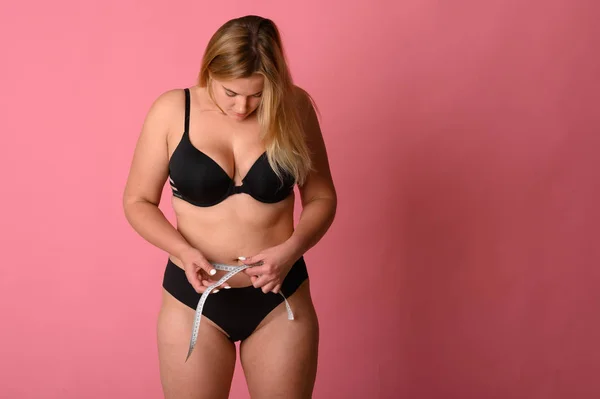 Girl wearing black bikini measures the size of the waist — Stock Photo, Image