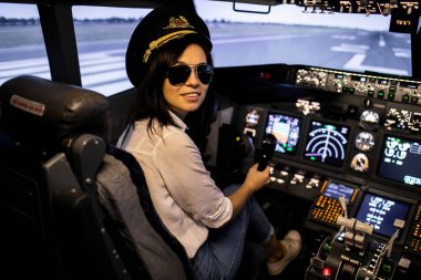 Uçak Kokpitinde Kadın Pilot. Güneş gözlüğü ve şapka takan pilot